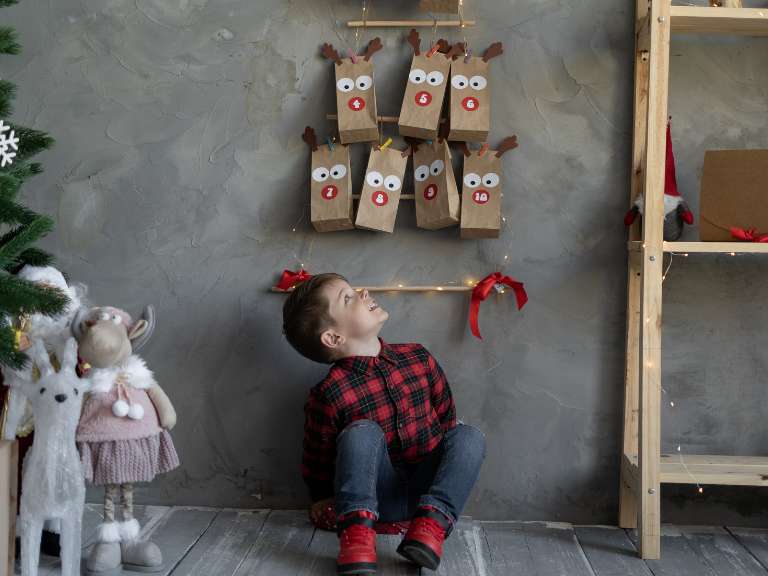 Kind sitzt vor einem selbstgemachten Adventskalender