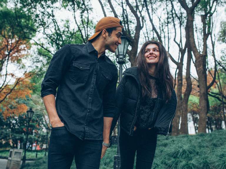 Junges Paar geht spazieren und schaut sich verliebt mit einem Lächeln im Gesicht an