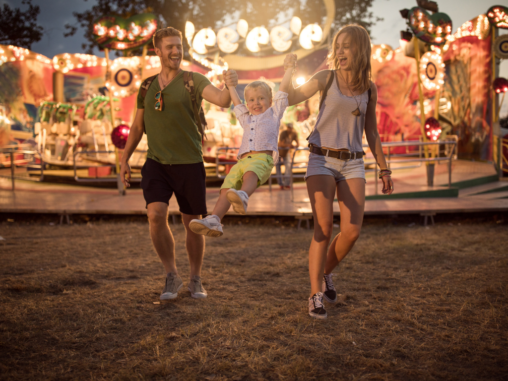 Junge Eltern geben ihren kleinen Sohn an den Händen und schwingen ihn in der Luft