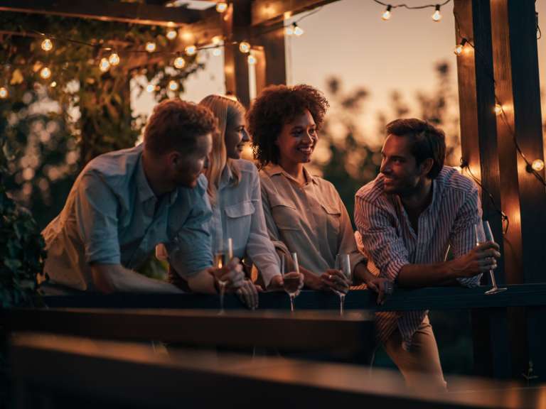 Zwei junge Paare trinken Sekt und lachen zusammen und reden miteinander
