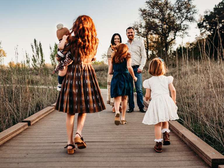 Eltern und vier Kinder laufen über einen Steg bei Sonnenschein