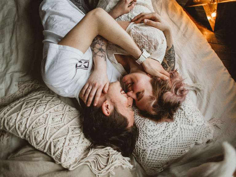 Junges Paar liegt im Bett und kuschelt