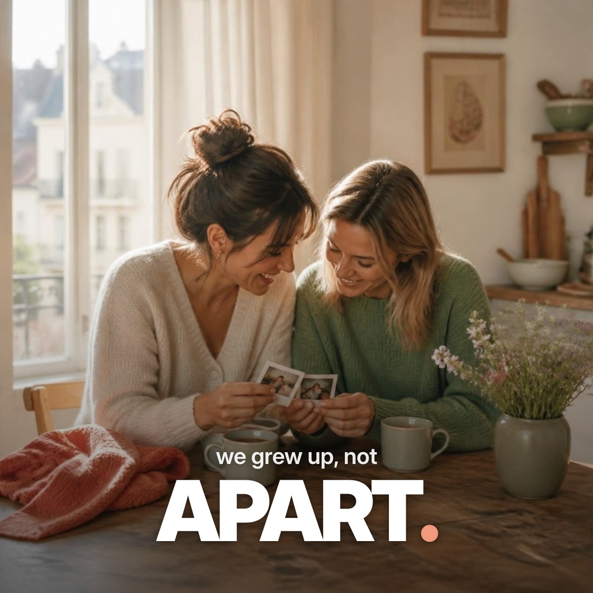 Schriftzug ‚we grew up, not APART.‘ über einem Foto zweier Freundinnen, die an einem sonnigen Küchentisch bei Tee lachend alte Sofortbilder aus ihrer Jugend betrachten.