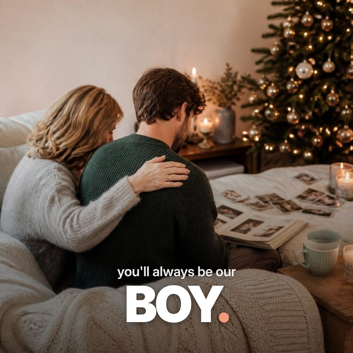 Schriftzug ‚you'll always be our BOY.‘ über einem Foto, auf dem ein erwachsener Sohn von hinten neben seiner Mutter auf dem Sofa sitzt und im weihnachtlichen Wohnzimmer bei Lichterketten ein altes Familienalbum durchblättert.