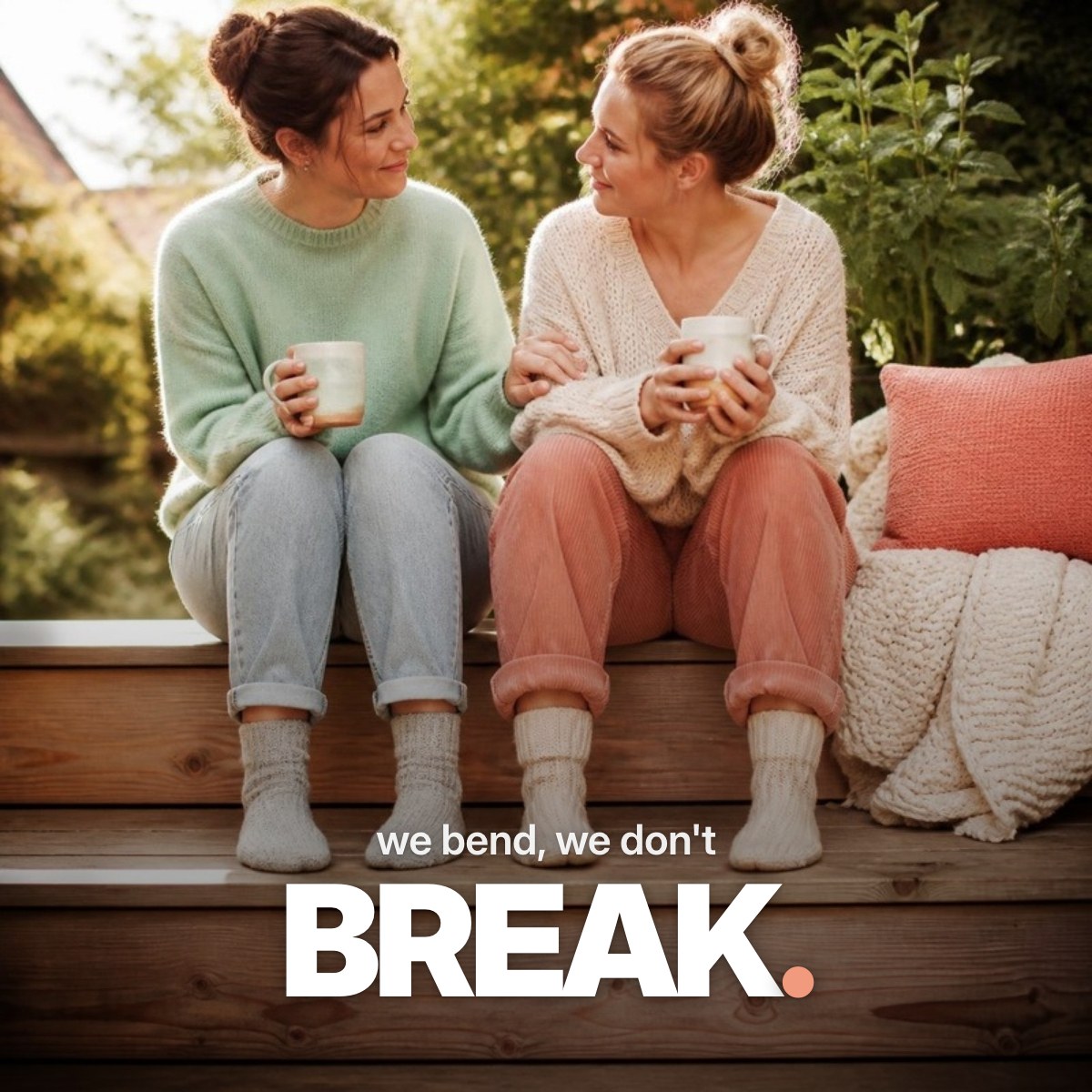 Schriftzug ‚we bend, we don't BREAK.‘ über einem Foto von zwei Freundinnen, die mit Teetassen auf sonnigen Holzstufen einer Veranda sitzen und sich versöhnlich die Hand auf den Arm legen.