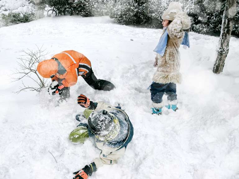 Drei Kinder spielen im Schneeanzug im Schnee