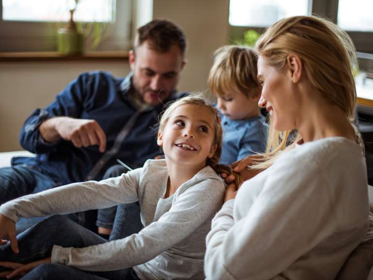 Junge Familie mit einem Sohn und einer Tochter sitzen auf dem Sofa und freuen sich