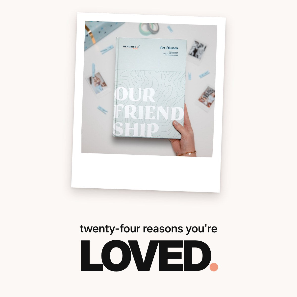Schriftzug ‚twenty-four reasons you're LOVED.‘ über dem mintgrünen Challengebuch für beste Freundinnen mit dem Cover ‚Our Friendship‘, umgeben von Sofortbildfotos, Holzklammern, Washi-Tape und einem Geschenkpaket.