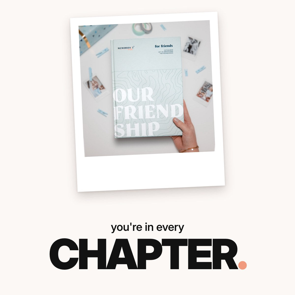 Schriftzug ‚you're in every CHAPTER.‘ über dem mintgrünen Challengebuch für beste Freundinnen in einer Hand, umgeben von Sofortbildfotos, Holzklammern, Washi-Tape und einem Geschenkpaket.