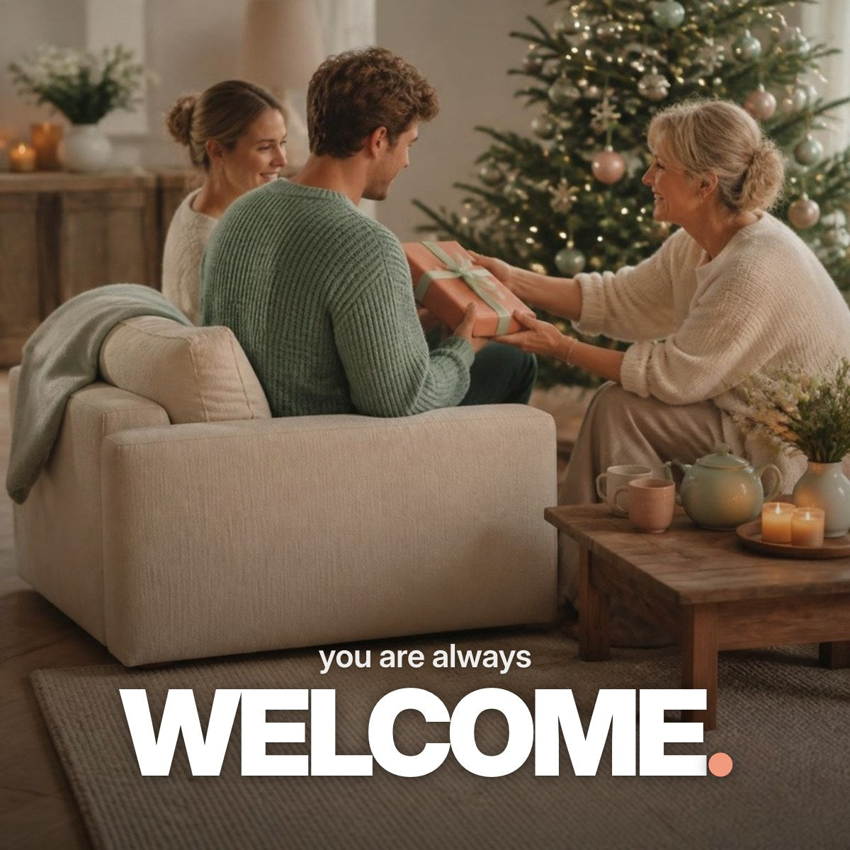 Schriftzug ‚you are always WELCOME.‘ über einem Foto eines jungen Paares in einem weihnachtlichen Wohnzimmer, dem ein kleines Geschenk in korallfarbenem Papier überreicht wird.