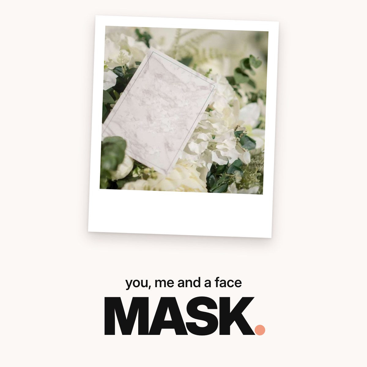 Schriftzug ‚you, me and a face MASK.‘ über einer leeren Karte in hellgrauer Marmoroptik, die in einem Arrangement aus weißen Blüten und grünen Zweigen steckt.